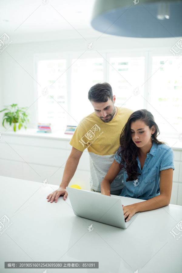 在厨房里用笔记本电脑的夫妇