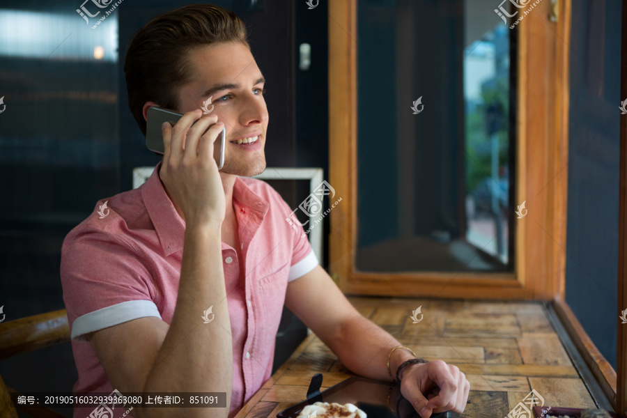 年轻人在咖啡店餐桌上使用手机