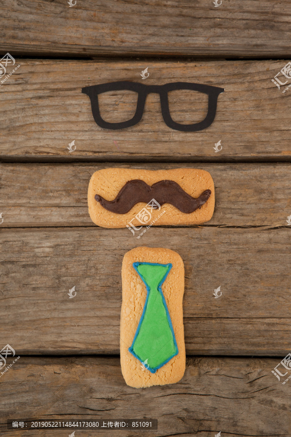 木桌上带小胡子和领带的曲奇