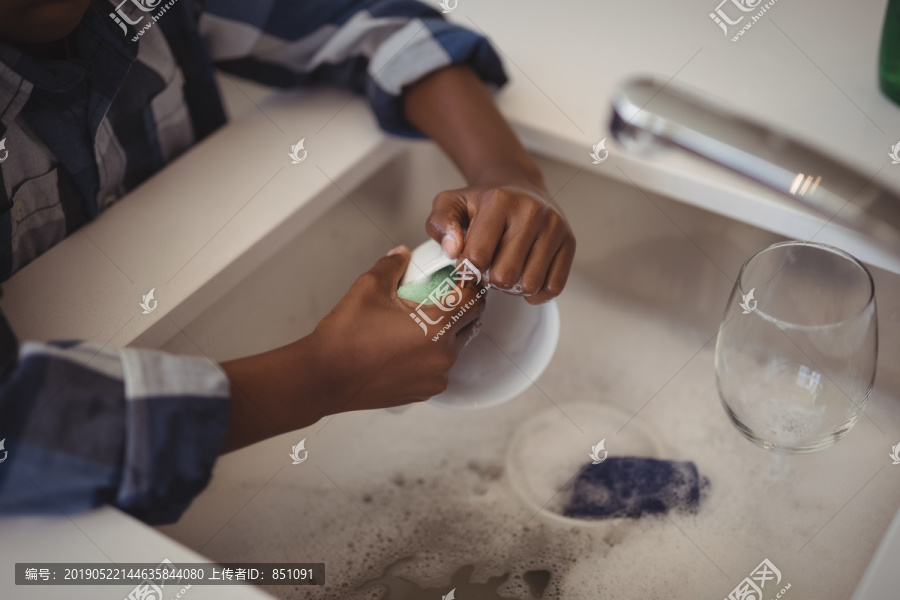 男孩在厨房水槽里洗杯子