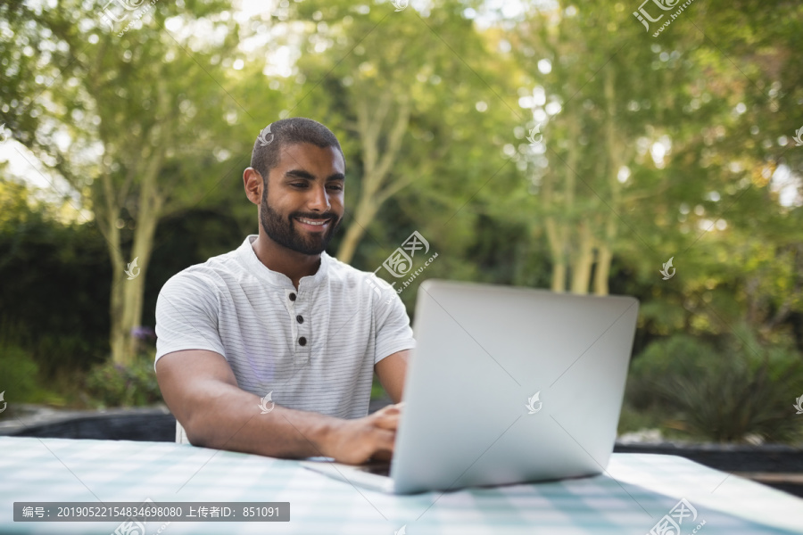 在露台上用笔记本电脑微笑的男人