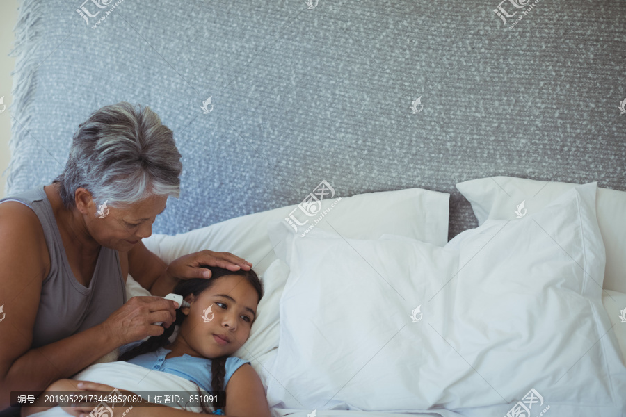 奶奶在床上检查生病孙女的体温