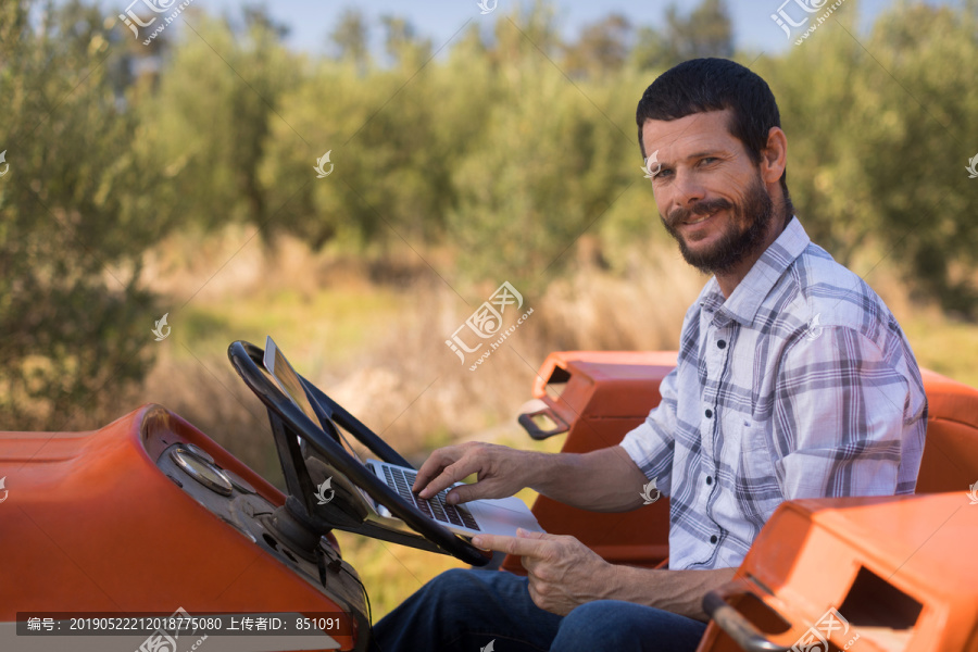 在拖拉机上使用笔记本电脑的男人
