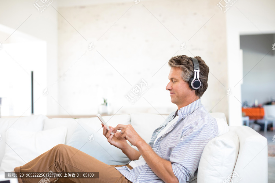 在家客厅里用手机听音乐的男人