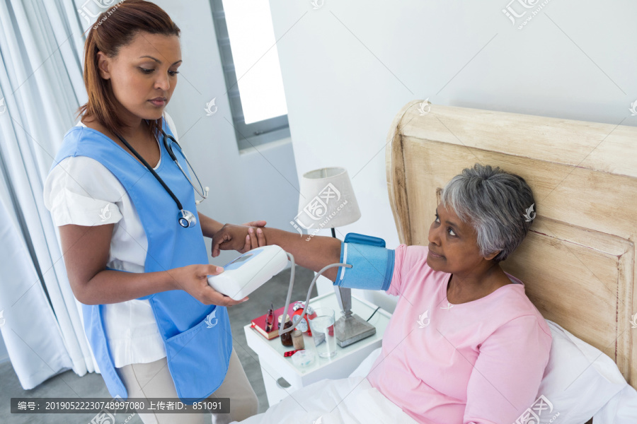 女医生测量卧房老年妇女血压