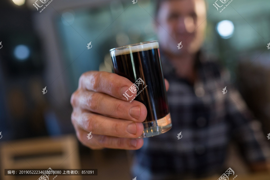 坐在酒吧里拿着啤酒杯的男人