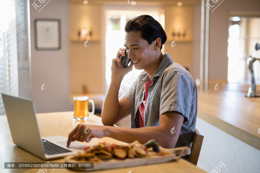 在餐馆里用手机交谈的男人