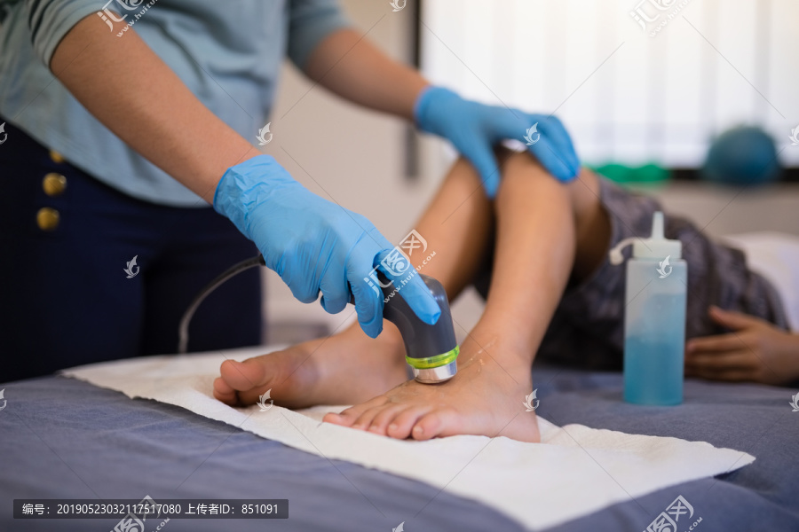 女治疗师戴着手套扫描男孩的脚