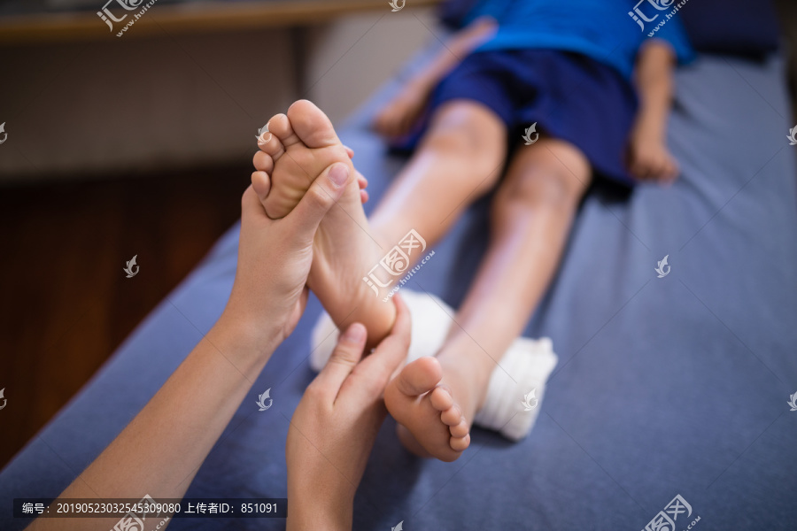 男童卧床接受女治疗师足底按摩
