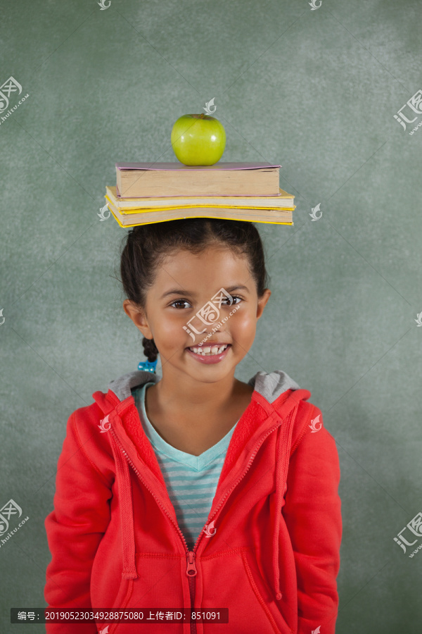 小女孩把书和苹果放在头上