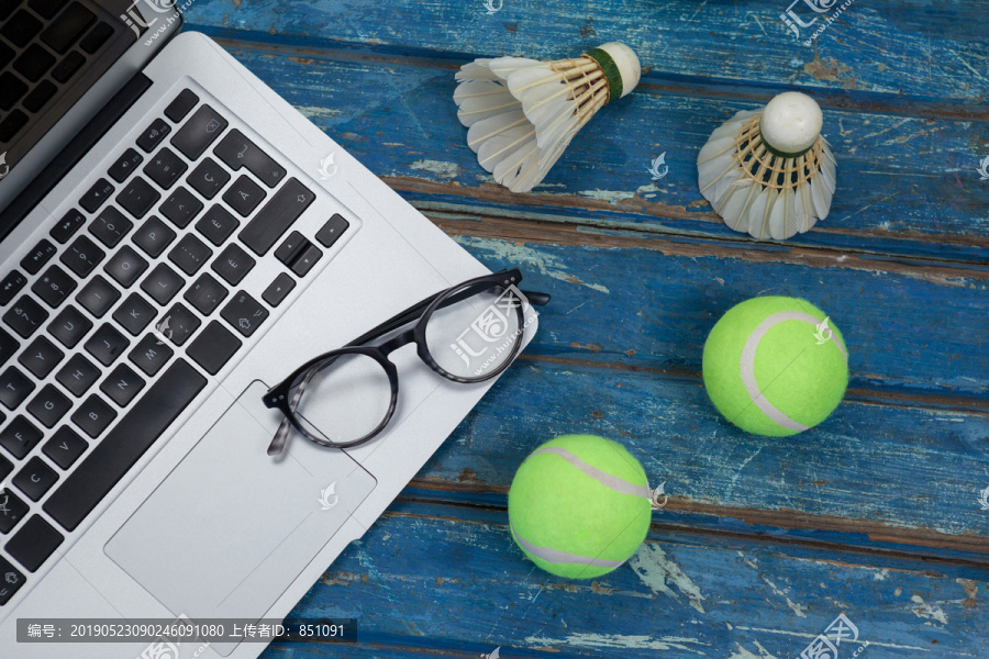 带网球羽毛球的笔记本电脑和眼镜