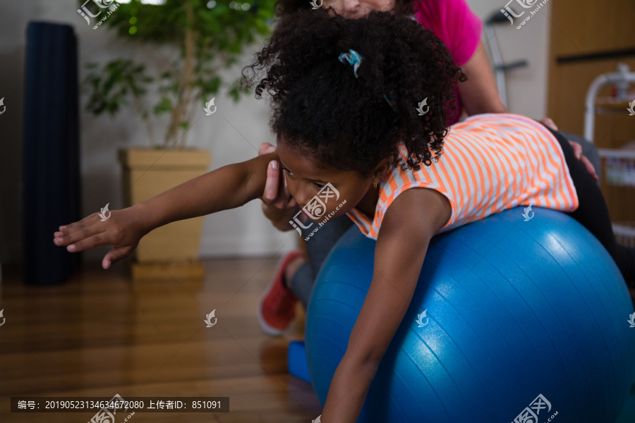 女理疗师帮儿童进行健身球运动