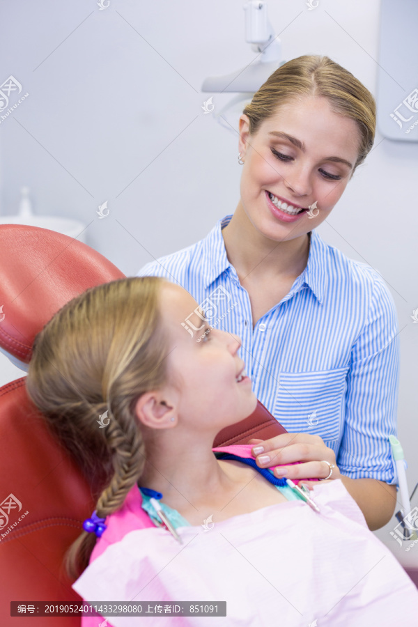 微笑的母亲在牙科诊所给女儿刷牙