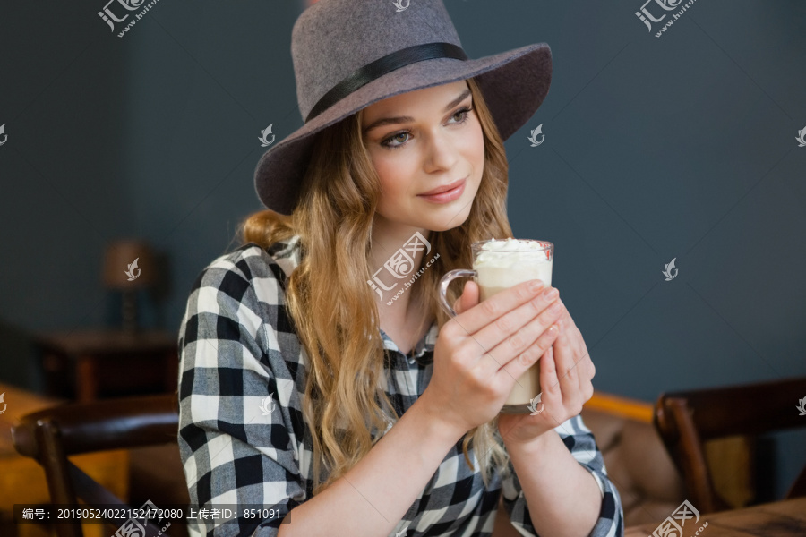 年轻女子边看边在咖啡厅拿冷咖啡