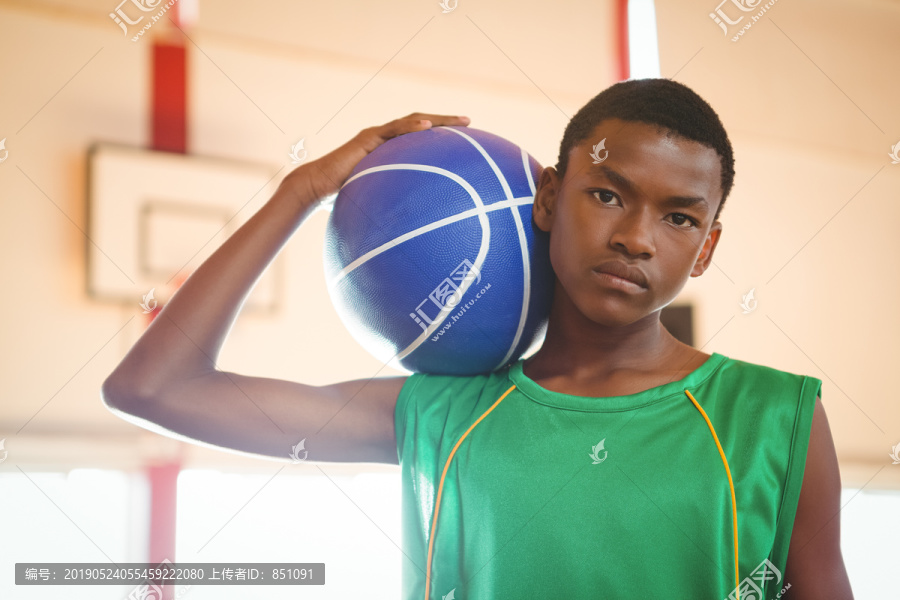 自信少年站在球场上打篮球的照片