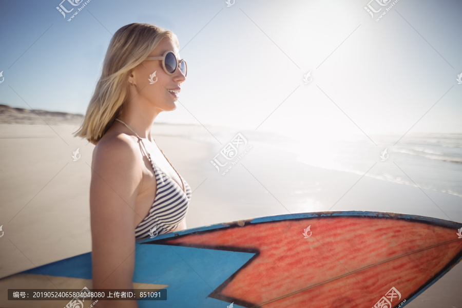 沙滩上拿着冲浪板的金发女人