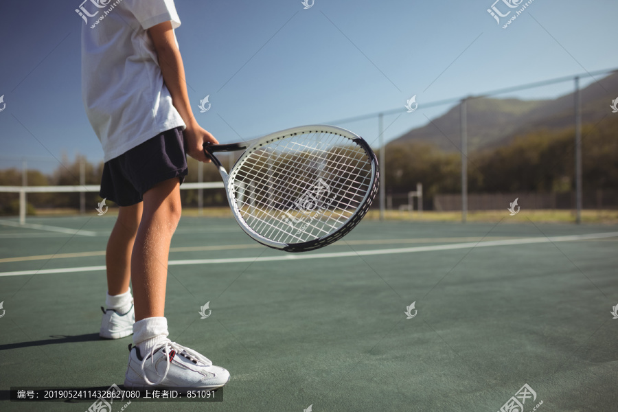 站在球场上拿网球拍的小女孩