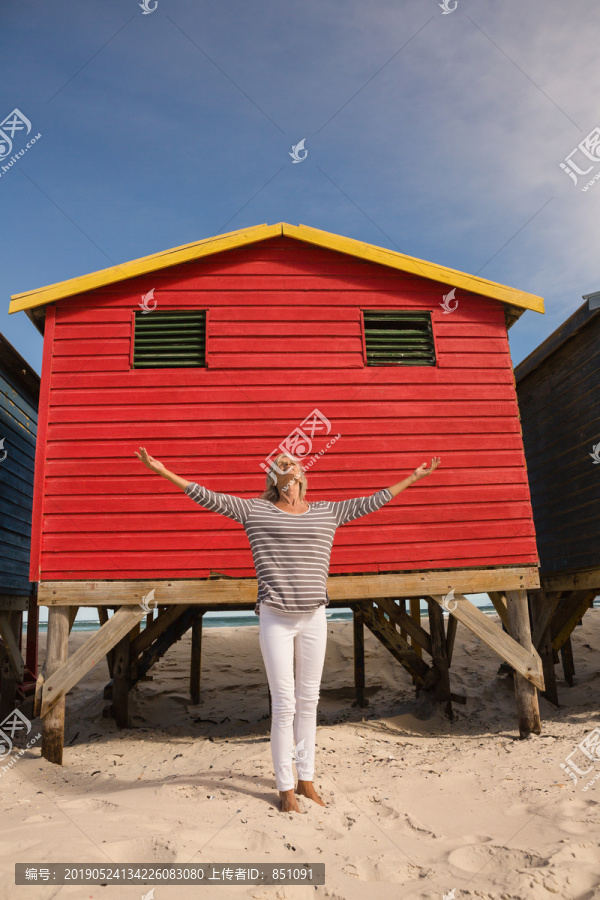 站在沙滩上靠着小屋的女人