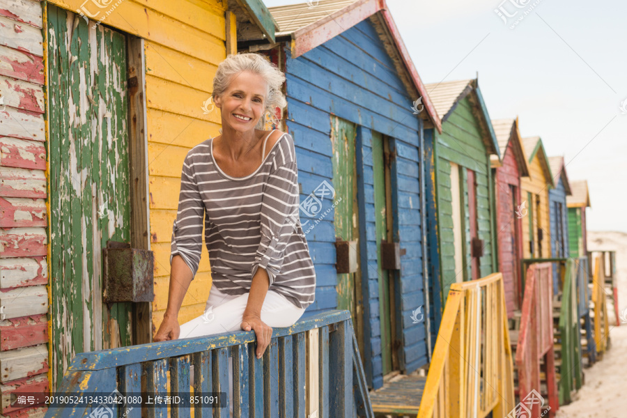 坐在海滩小屋栏杆上微笑的女人