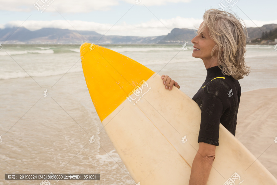 站在沙滩上带着冲浪板的女人