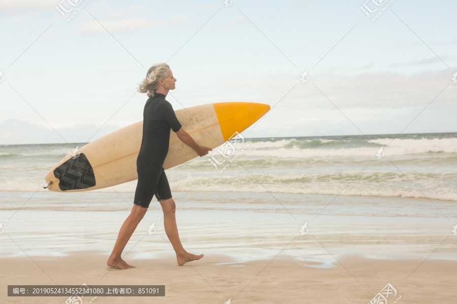 背着冲浪板站在海滩上的妇女