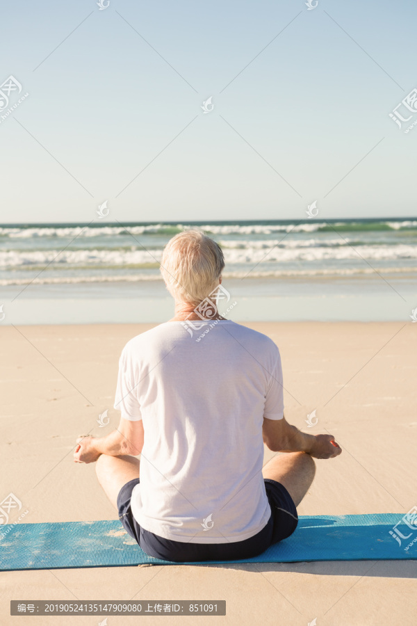 坐在沙滩上练瑜伽的老人
