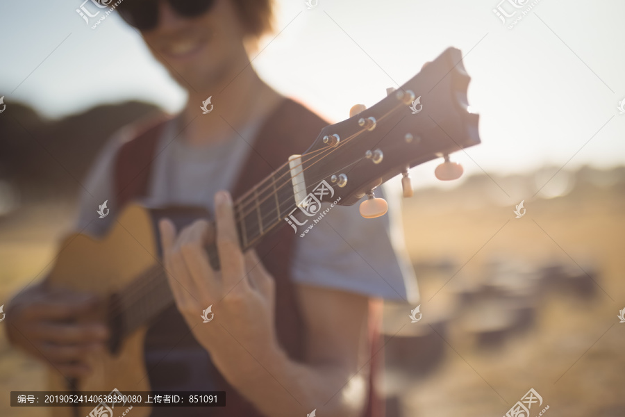 森林里站在田野上弹吉他的年轻人
