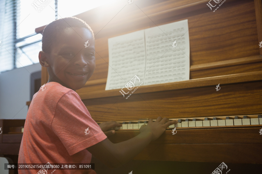 在学校教室里弹钢琴的男孩