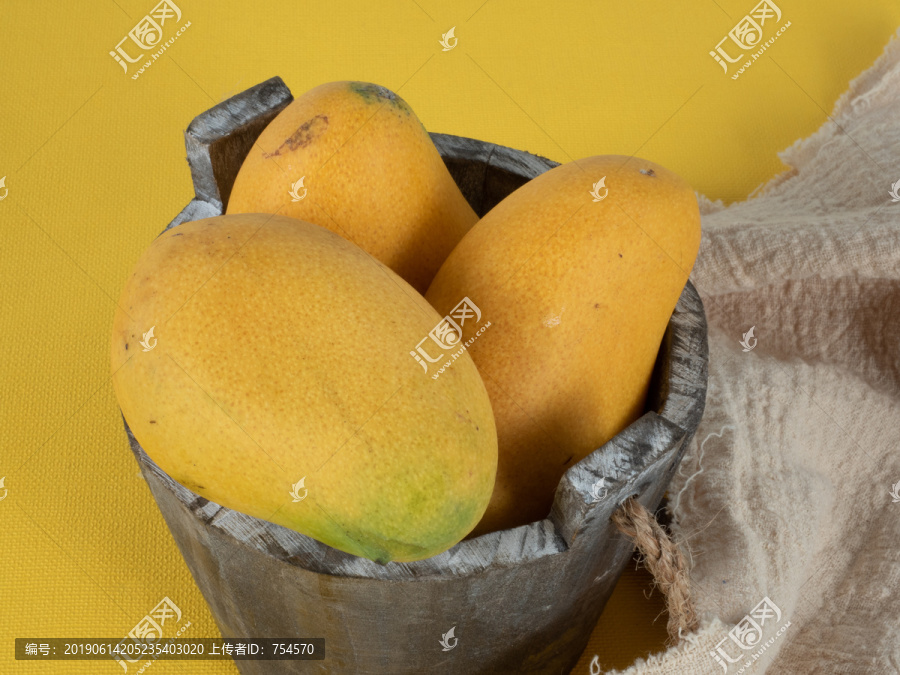 黄色背景里木桶里的芒果