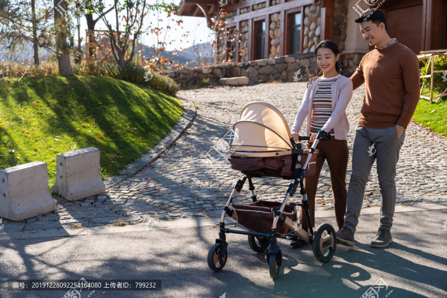 年轻夫妻推着婴儿车散步
