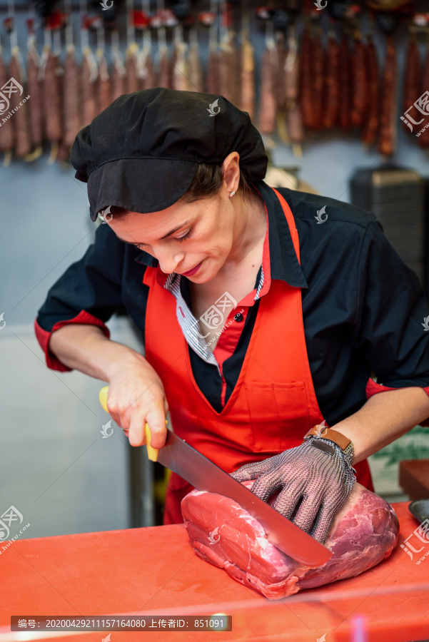 用金属网手套在肉店切鲜肉的妇女