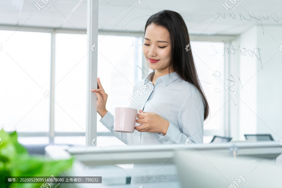 年轻商务女士在办公室喝咖啡