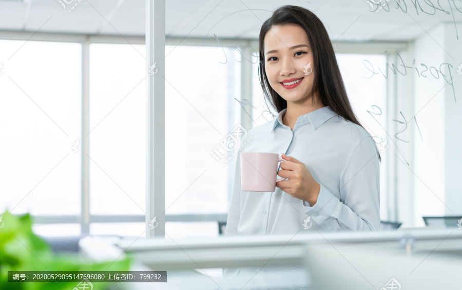 年轻商务女士在办公室喝咖啡