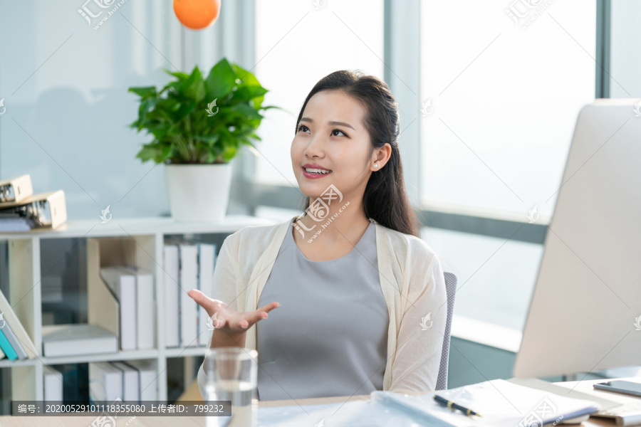 年轻女子在办公室拿着一个橙子