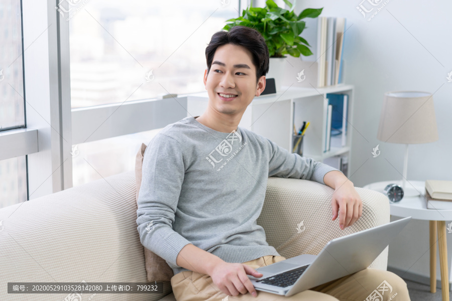 年轻男子在沙发上使用笔记本电脑