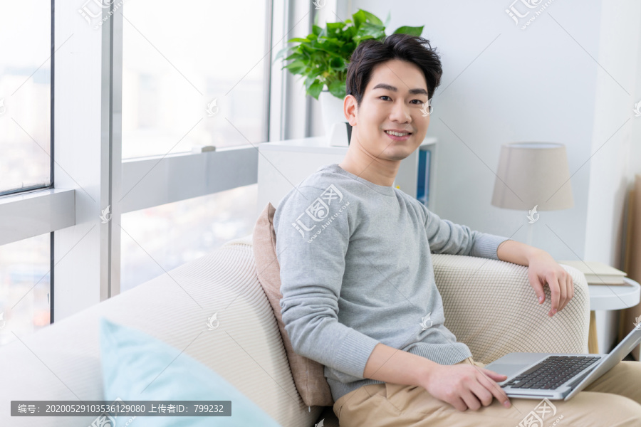 年轻男子在沙发上使用笔记本电脑