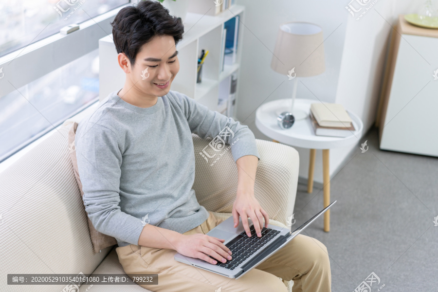 年轻男子在沙发上使用笔记本电脑