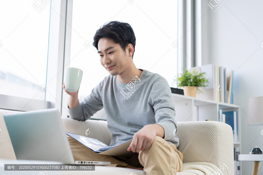 年轻男子在沙发上使用笔记本电脑