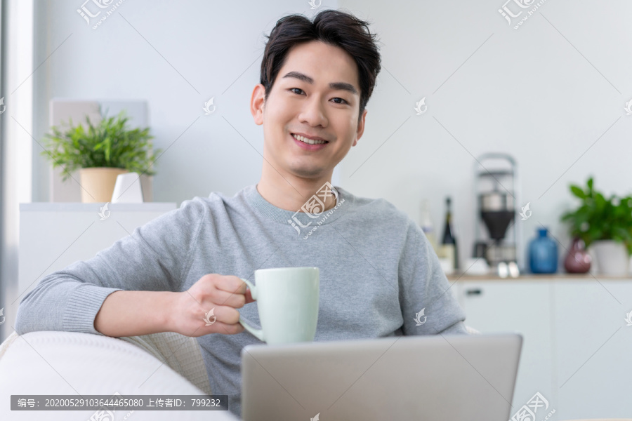 年轻男子在沙发上使用笔记本电脑