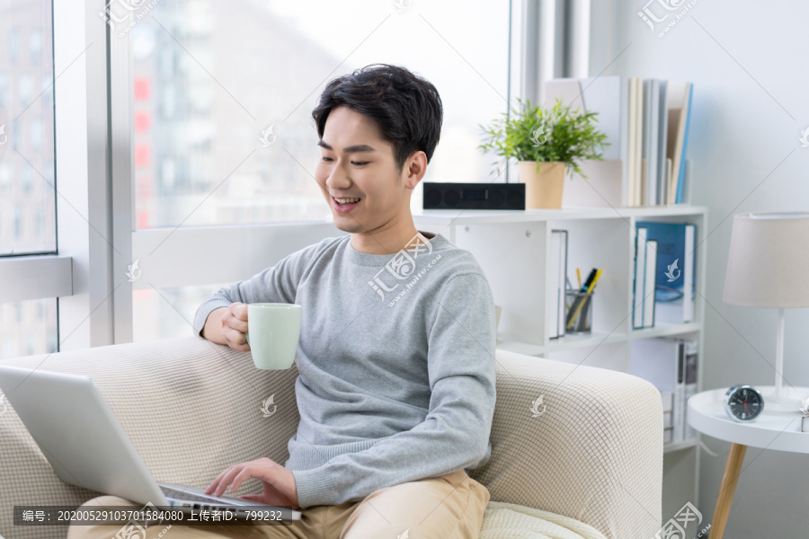 年轻男子在沙发上使用笔记本电脑