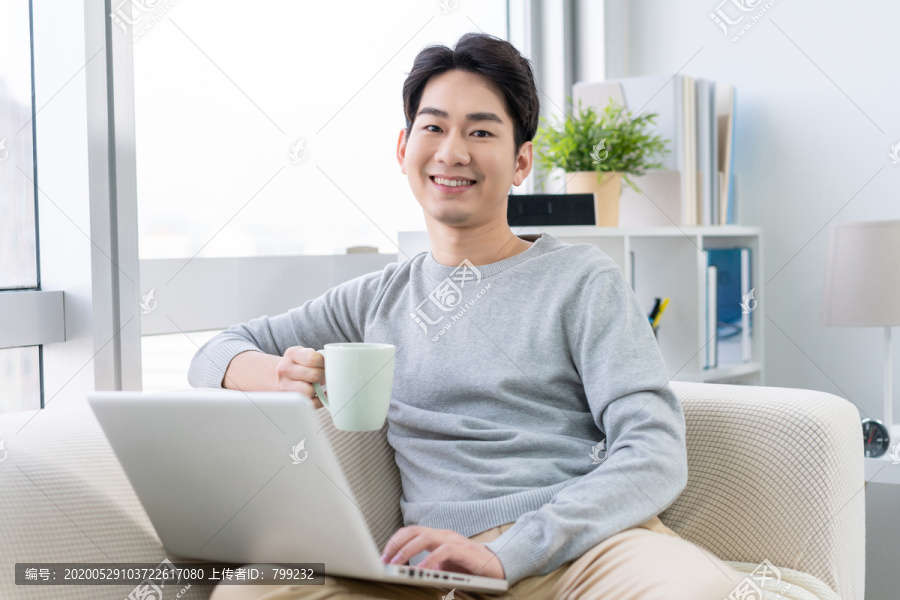 年轻男子在沙发上使用笔记本电脑