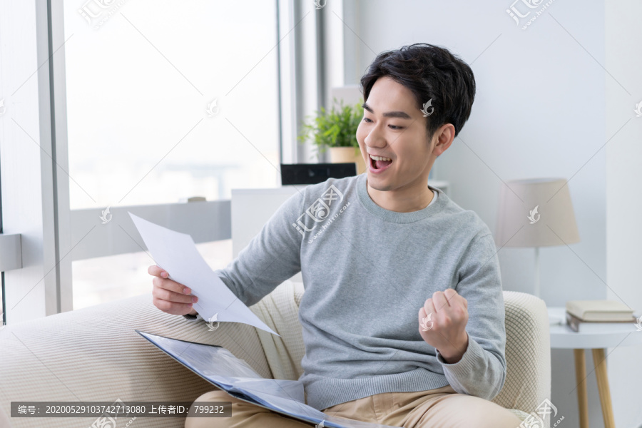 年轻男子在沙发上看文件