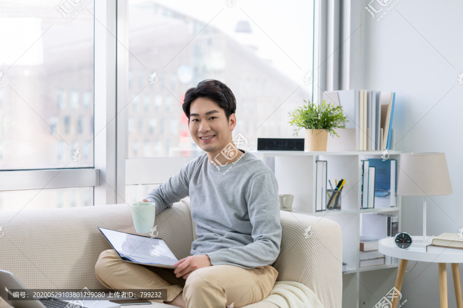 年轻男子在沙发上使用笔记本电脑