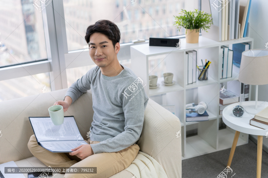 年轻男子在沙发上看文件