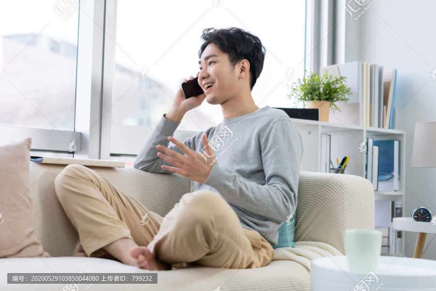 年轻男子坐在沙发上打电话