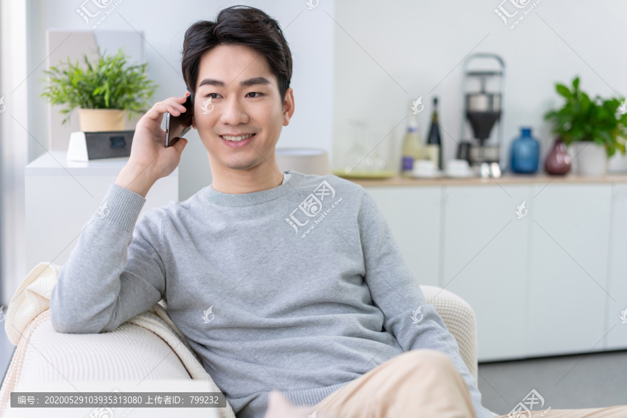 年轻男子坐在沙发上打电话