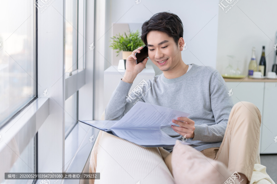 年轻男子坐在沙发上打电话