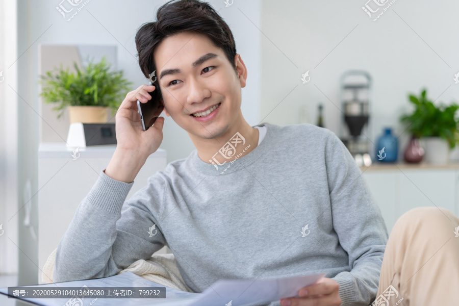年轻男子坐在沙发上打电话