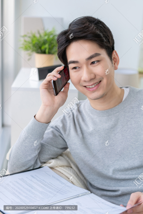 年轻男子坐在沙发上打电话