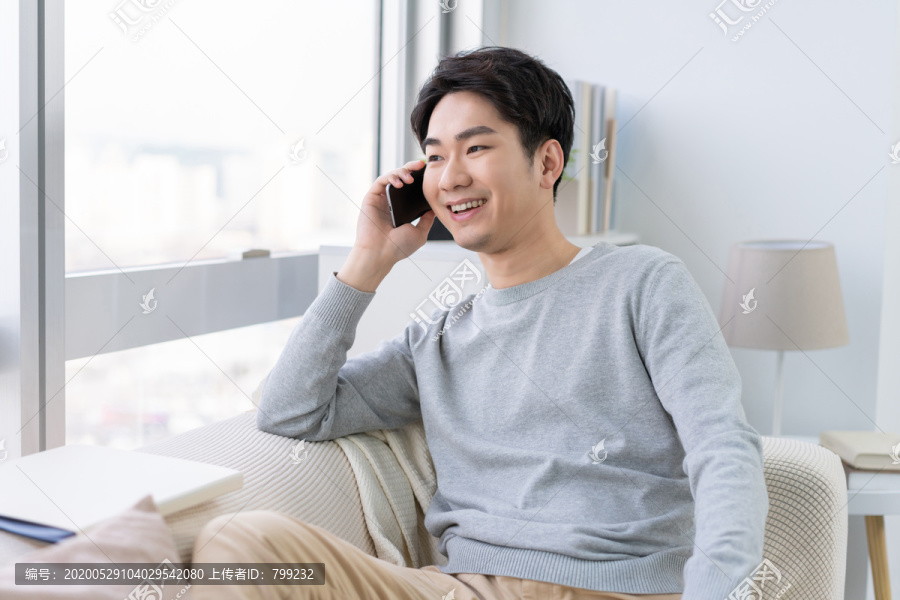 年轻男子坐在沙发上打电话